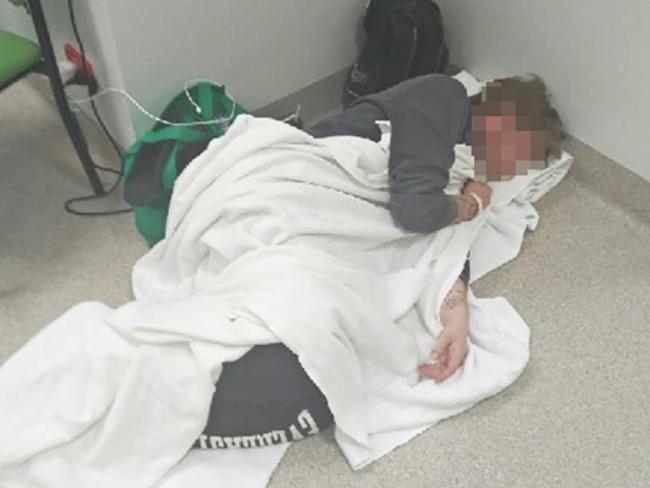 A patient waiting for treatment at the Royal Hobart Hospital makes a bed on the floor.