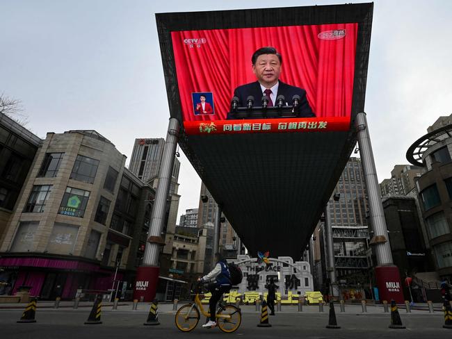 TOPSHOT - An outdoor screen shows a live news coverage of Chinaâs President Xi Jinping delivering a speech during the closing session of the National People's Congress (NPC) at the Great Hall of the People, along a street in Beijing on March 13, 2023. (Photo by JADE GAO / AFP)