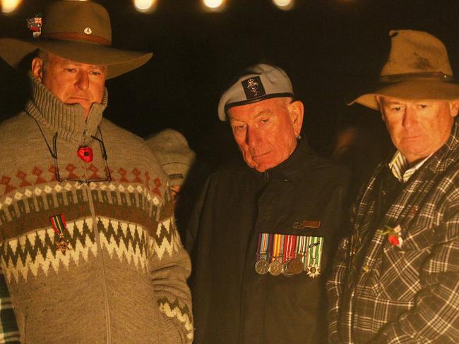 Men gather early at the Eternal Flame ahead of the Anzac Day dawn service at the Shrine of Remembrance in Melbourne. Picture: Hamish Blair