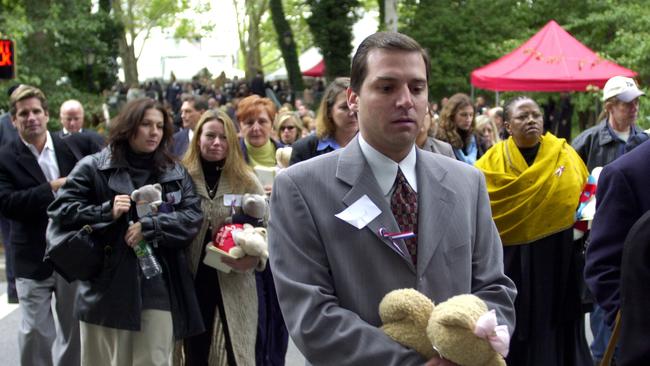 A mourner carries a teddy bear as he leaves a private memorial service for Cantor Fitzgerald employees who lost their lives in the 9/11 terrorist attack on the World Trade Center, in New York's Central Park on October 1, 2001.