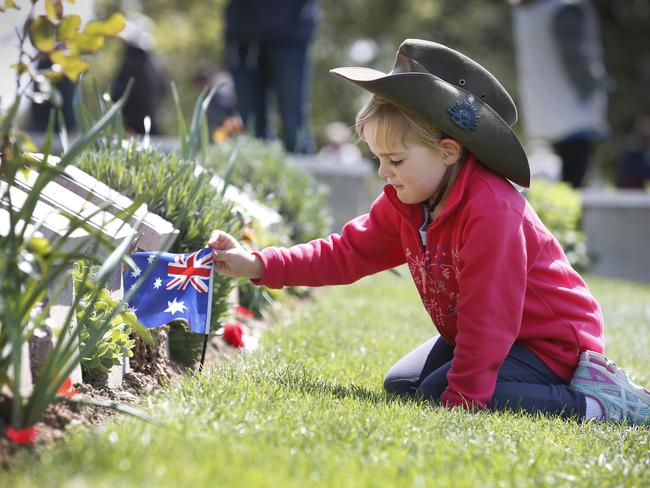 Baby steps ... Caitlyn Dickason 5, of Whittlesea Victoria, places an Australian Flag at a head stones of Australian soldier. Picture: David Caird.