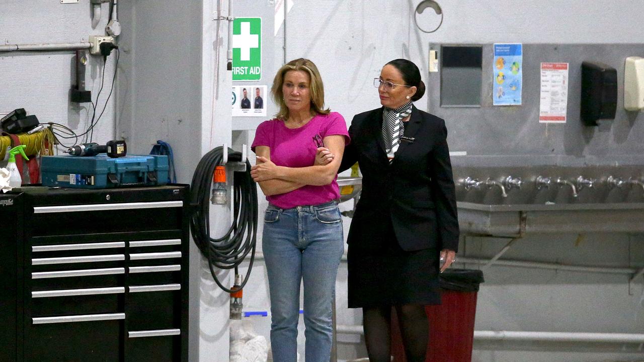 A staff member comforts Australian cricketer Shane Warne's personal assistant Helen Nolan (left) as she waits for the coffin bearing Warne to be brought out from a private jet at the Melbourne airport. (Photo by Aaron FRANCIS / AFP)