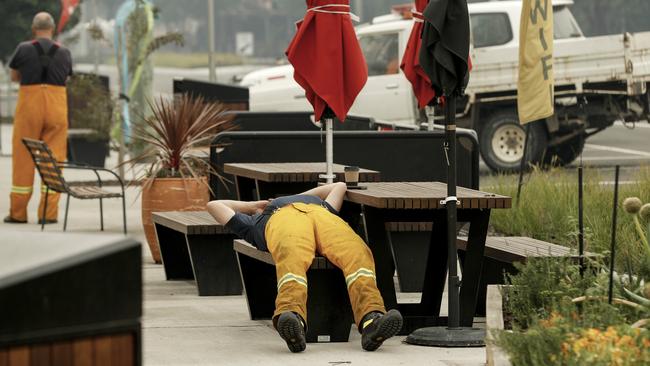 A tired firefighter rests outside a cafe in Cann River. Picture: Getty Images