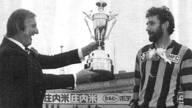 Jack Hamilton presents Hawthorn's Michael Tuck with a trophy after the Hawks won the Aussie Bowl in Yokohama, Japan in 1986.