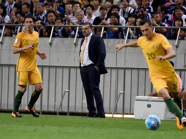 Australian head coach Ange Postecoglou (C) looks at his players.