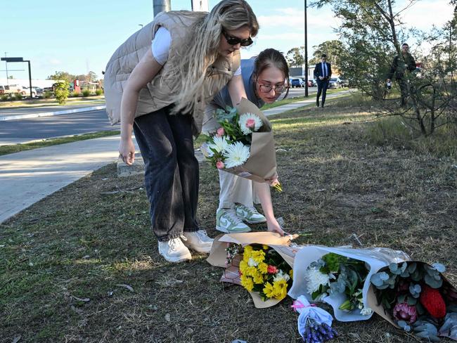 People place flowers next to a road some 500 meters from the site of a bus crash. Picture: AFP