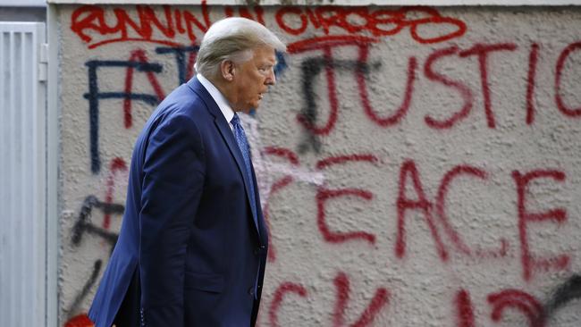 Donald Trump walks from the White House past graffiti in Lafayette Park to visit St. John's Church in Washington last week. Picture: AP