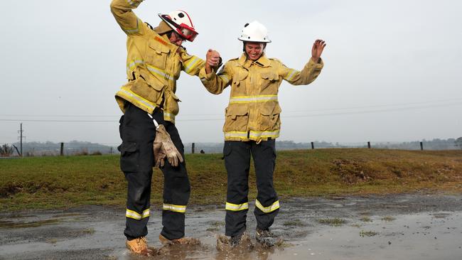 Milton RFS volunteers Glenn Patterson and Tess Oss-Emer dance in the rain. Picture: Jonathan Ng