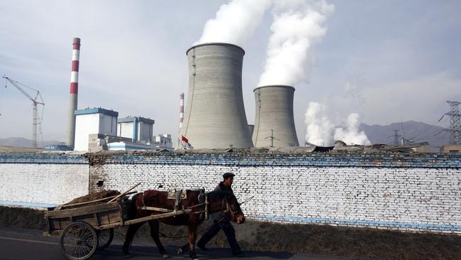 A farmer leads a cart as he walks past cooling towers of the coal-fired Datong County Thermal Power Plant. Picture: Getty Images/File