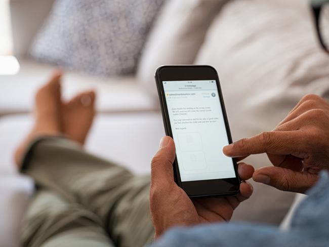 Closeup of a man hand holding cellphone with internet browser on screen. Man with spectacles relaxing sitting on couch while looking at mobile phone. Closeup of mature latin man using smartphone to checking email at home.