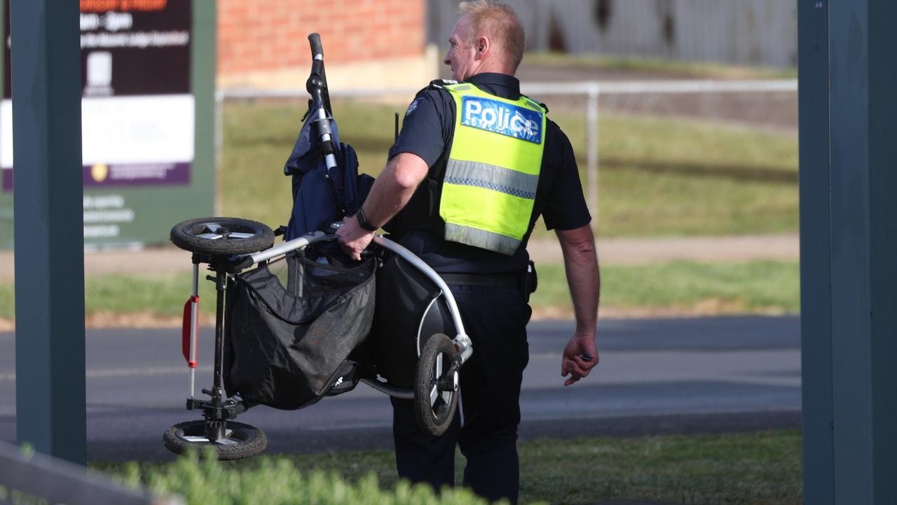 A police officer carries away a pram. Picture: Brendan Beckett