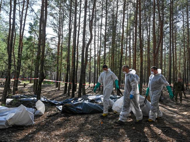 Forensic technicians carry a bodybag at the site of a mass grave in a forest on the outskirts of Izyum. Picture: AFP