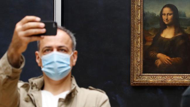 A visitor wearing a protective face mask takes a selfie in front of the Mona Lisa on the reopening day of the Louvre. Picture: AFP.