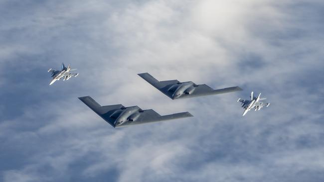 Two Royal Australian Air Force EA-18G Growler jets fly in formation with two United States Air Force B-2 Bomber aircraft.