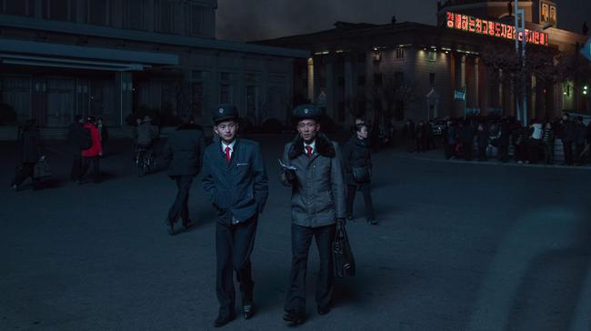 North Korean students illuminated by a public television screen walk past the central station in Pyongyang on November 16, 2017. Picture: AFP / Ed Jones.