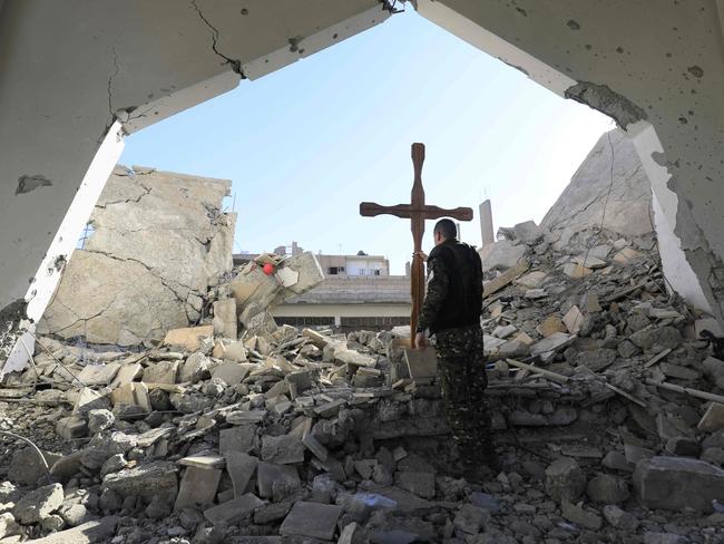 A member of the Syrian Arab-Kurdish forces places a cross in the rubble ahead of a Christmas celebration in the liberated Syrian city of Raqqa. Picture: Delil Souleiman/AFP