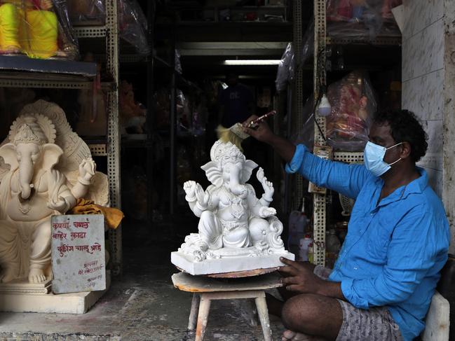 An Indian artist wearing a face mask as a precaution against the coronavirus paints an idol of Hindu god Ganesha at his workshop in Mumbai. Picture: AP