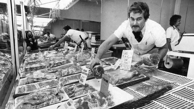 Butcher David Robertson putting meat on display in the Denmark Meat Shop in Rundle Mall, 1981.