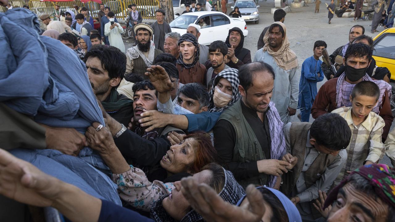 Displaced Afghans reach out for aid from a local Muslim organisation at a makeshift IDP camp. Picture: Paula Bronstein /Getty Images