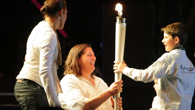 Louise Sauvage receives the torch at the relighting of Sydney’s Olympic cauldron.