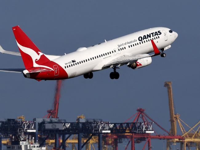 This picture taken on December 6, 2023 shows a Qantas Airways Boeing 737-800 passenger aircraft taking off at Sydneyâs Kingsford Smith international airport in front of a container ship berthed at the Port Botany container terminal. (Photo by DAVID GRAY / AFP)