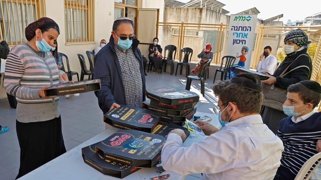 People receive pizzas after getting doses of the Pfizer-BioNtech COVID-19 coronavirus vaccine, at Clalit Health Services in the Israeli city of Bnei Brak. Picture: Jack Guwz/AFP