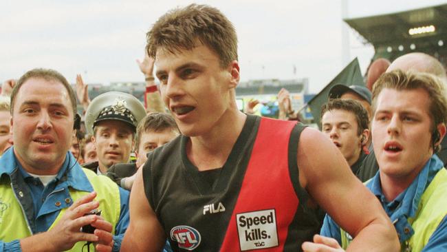 Security whisks away Matthew Lloyd after his 100th goal against North Melbourne in 2000. 