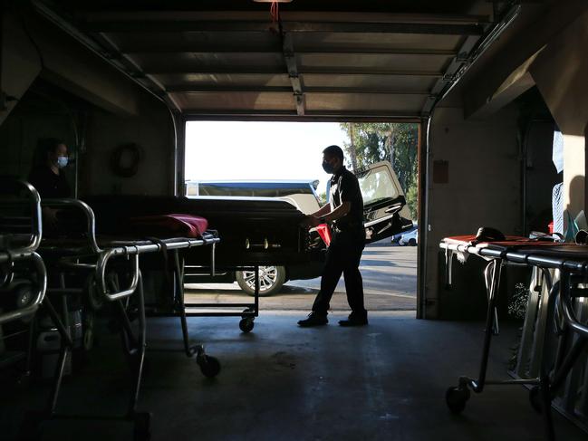 Funeral attendant Sam Deras (C) helps wheel the coffin of a person who died after contracting COVID-19 towards a hearse in California. Picture: Getty Images/AFP