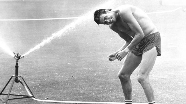 Melbourne great Robbie Flower cools off under a sprinkler at training.