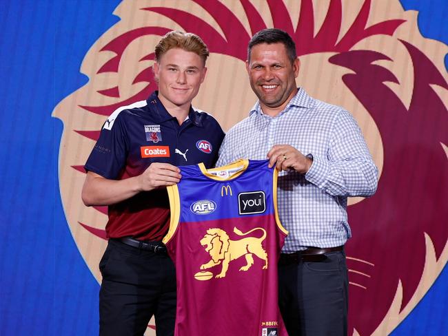 MELBOURNE, AUSTRALIA - NOVEMBER 20: The number five pick, Levi Ashcroft is presented his Brisbane jumper by Chris Johnson during the 2024 Telstra AFL Draft at Marvel Stadium on November 20, 2024 in Melbourne, Australia. (Photo by Michael Willson/AFL Photos via Getty Images)