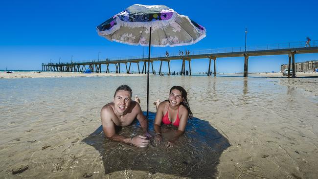 Renato Lovisa and Natasha Romano in sun, sea and shade at Glenelg, Adelaide, yesterday. Picture: Roy Vandervegt