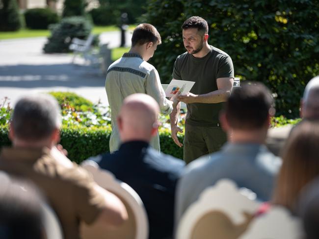 Ukrainian President Volodymyr Zelenskyy hands over a Ukrainian national passport to a son of a Ukrainian serviceman killed in action against Russian troops. Picture: Getty Images