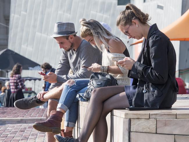 People using their phone in fed square in Melbourne. Picture: Jason Edwards
