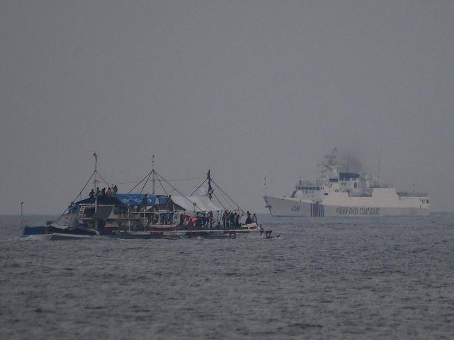 A China Coast Guard ship, right, sails past a Philippine fishing boat in the disputed South China Sea. Picture: AFP