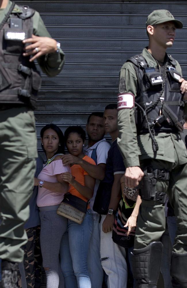 Locals are surrounded by Venezuelan Bolivarian National Guards officers as they line up outside of a supermarket to buy food in Caracas, Venezuela. Protests and looting in western Venezuela over food shortages has left at least seven people dead and many more injured. Picture: AP/Fernando Llano