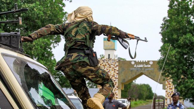 A fighter leaps from a military convoy vehicle accompanying the governor of Sudan's Darfur State during a stopover at Gedaref University in August 2023. Picture: AFP