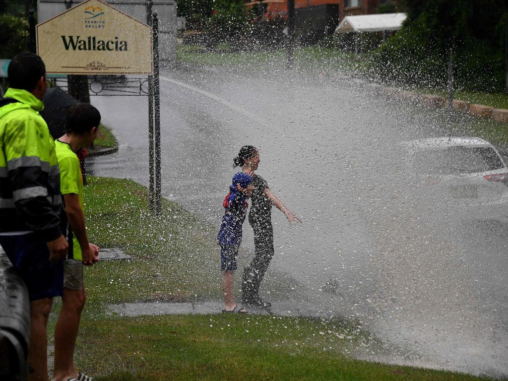 Children getting sprayed with floodwaters. Picture: Saeed KHAN / AFP