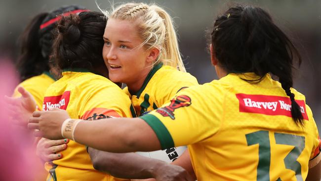 Meg Ward celebrates with Jillaroos teammates after scoring a try.