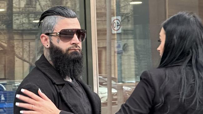 Senior Finks bikie, John Pahoumidis, leaves the County Court with his partner after pleading guilty to assaulting a former member of the outlaw motorcycle gang. ,