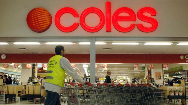 An employee collects shopping trolleys outside a Coles supermarket