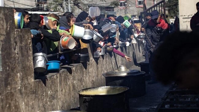 Displaced Palestinians hold empty pots as they line up for food aid in a refugee camp in southern Gaza. Picture: Haitham Imad/Shutterstock/WSJ