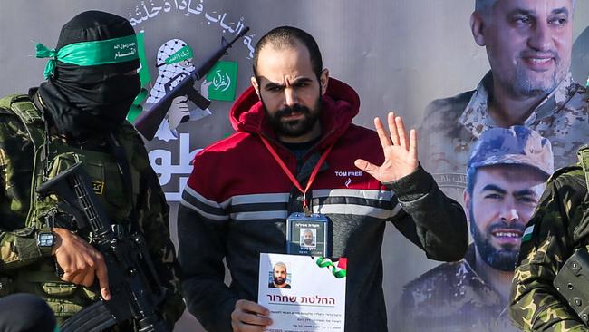 Palestinian militant group Hamas fighters escort Israeli hostages Yarden Bibas on a stage before handing him over to a Red Cross team in Khan Yunis on February 1, 2025, as part of fourth hostage-prisoner exchange. (Photo by Eyad BABA / AFP)