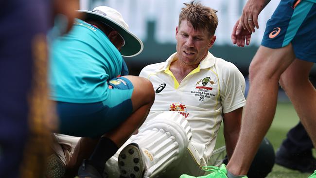 David Warner is helped from the ground after retiring hurt after reaching 200 . Picture by Michael Klein