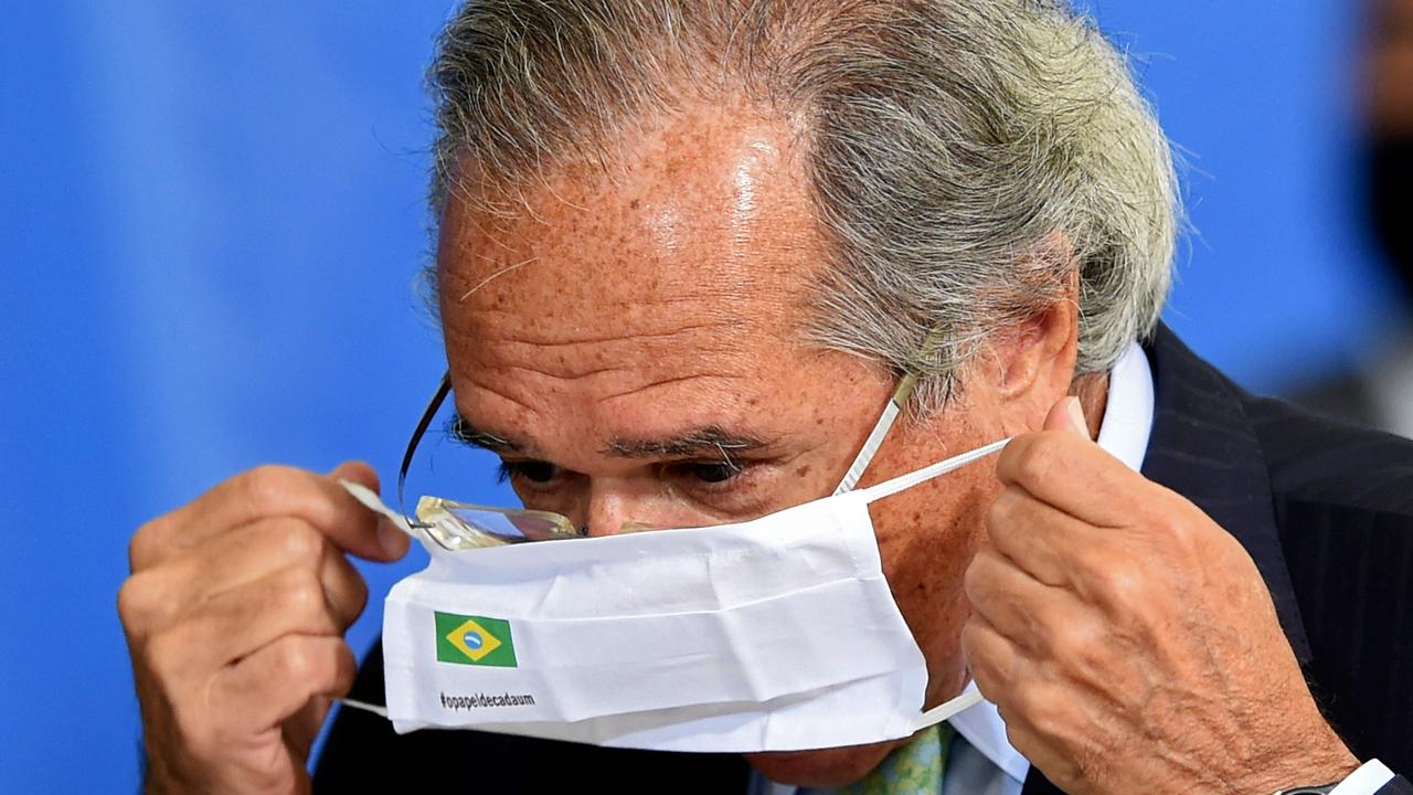 Brazilian Minister of Economy Paulo Guedes puts on a face mask during a ceremony to sign a decree facilitating small business access to credit to fight the economic impacts from COVID in Brazil. Picture: EVARISTO SA / AFP