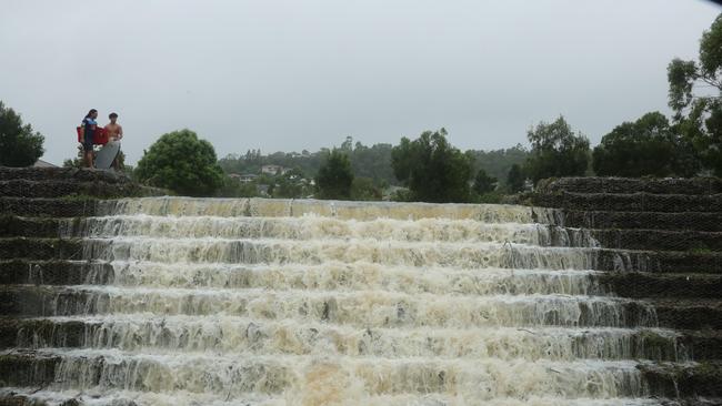 Floodwaters cascade from Flooded Gum Park at Pacific Pines. Picture: Glenn Hampson