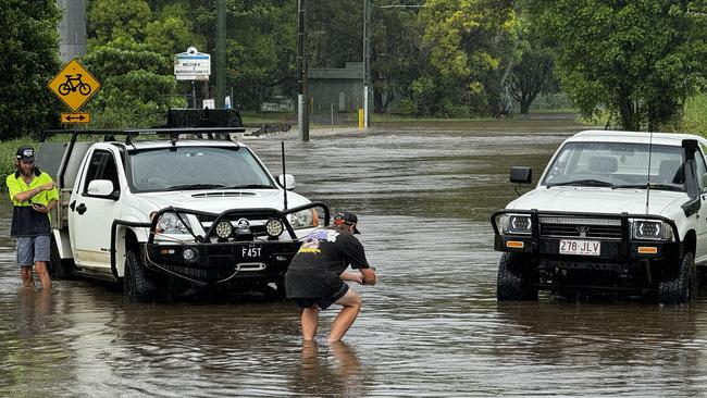 Locals testing the depths of the water over the service road flooded by Martins Creek at Kunda Park. Picture – Mark Furler.