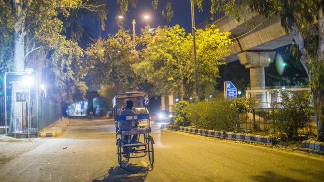 A rickshaw driver rides down a deserted Delhi street. Picture: Getty Images