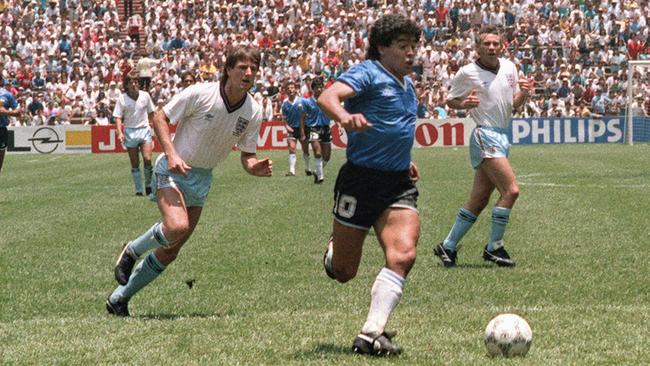 (FILES) In this file photo taken on June 22, 1986 Argentinian forward Diego Armando Maradona runs past English defenders Terry Butcher (L) and Terry Fenwick (2nd L) on his way to scoring his second goal during the World Cup quarterfinal soccer match between Argentina and England.Argentina advanced to the semifinals with a 2-1 victory.  AFP PHOTO - Argentinian football legend Diego Maradona passed away on November 25, 2020 (Photo by STAFF / AFP)