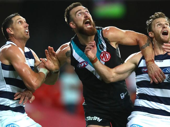 GOLD COAST, AUSTRALIA - AUGUST 14: Charlie Dixon of the Power (center) is wrapped up by Geelong defense during the round 12 AFL match between the Geelong Cats and the Port Adelaide Power at Metricon Stadium on August 14, 2020 in Gold Coast, Australia. (Photo by Jono Searle/AFL Photos/via Getty Images)