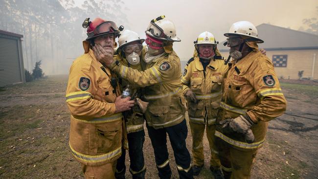 Bawley Point RFS captain John Sharpe (red helmet) was overcome with emotion as his colleagues helped him extinguish a blaze surrounding his home on December 5. Picture: Gary Ramage